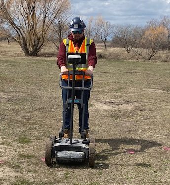 Structure Scan technician operating a GPR cart in an open field
